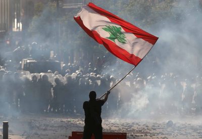 A demonstrator waves the Lebanese flag in front of riot police during a protest in Beirut, Lebanon, August 8, 2020. REUTERS/Goran Tomasevic     TPX IMAGES OF THE DAY