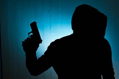 Silhouetted man with gun against blue wall background